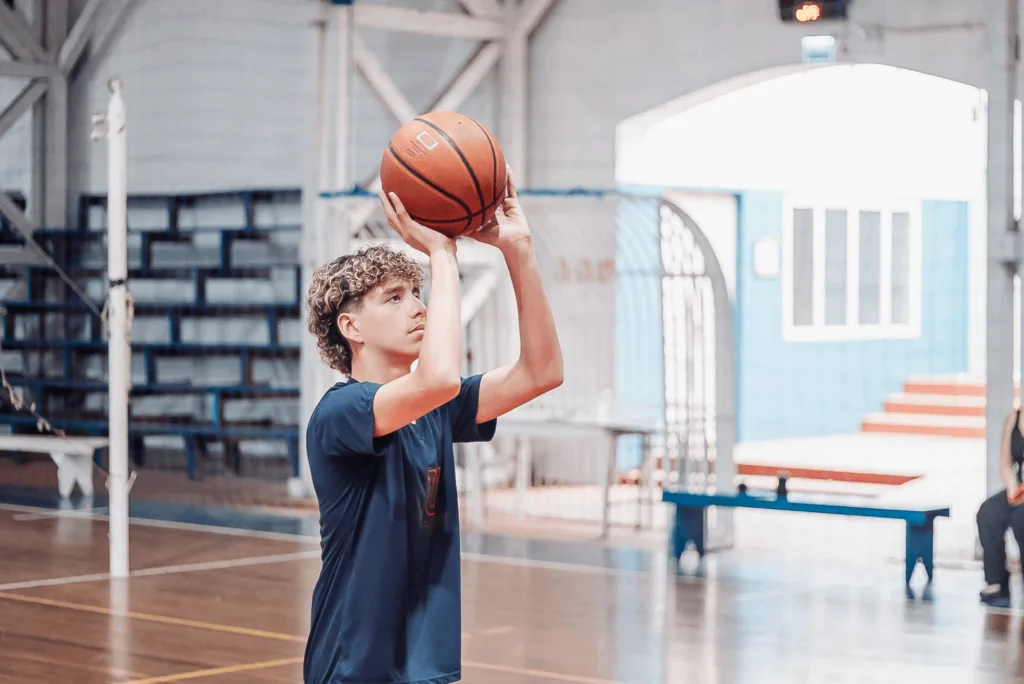 Aluno praticando basquete no ginásio do colégio